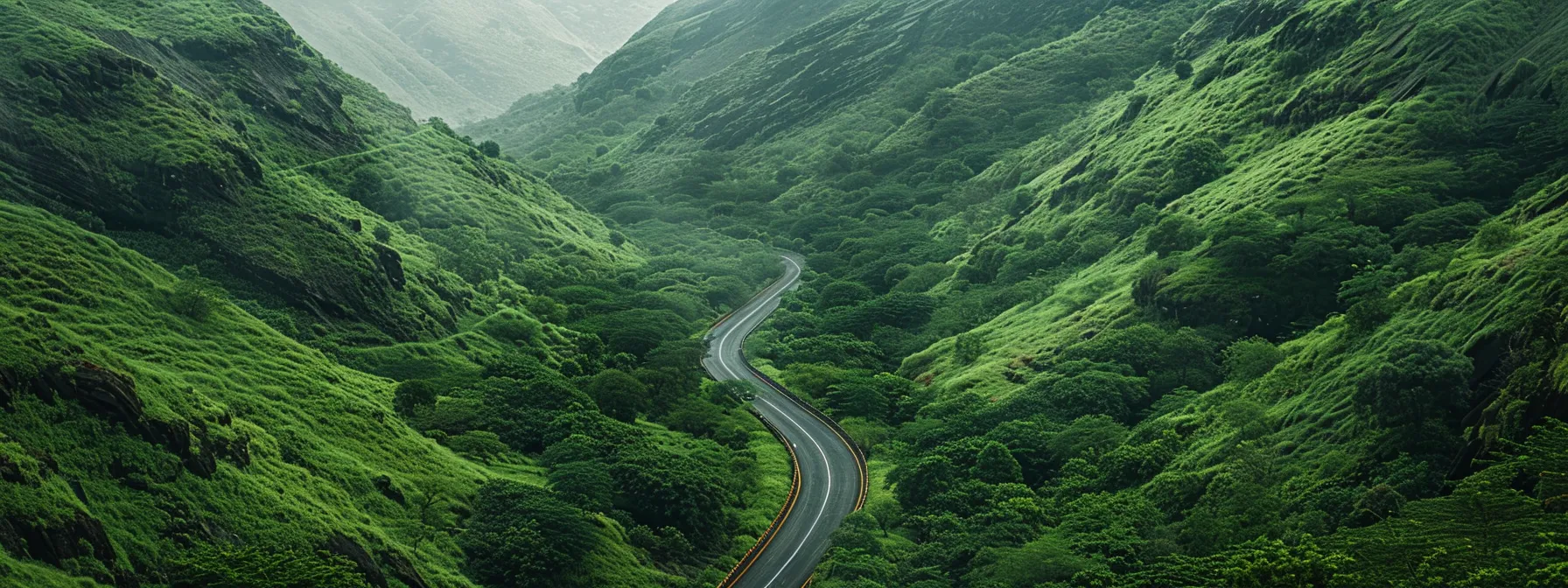 a winding road stretches through lush green mountains, leading to a breathtaking scenic overlook.